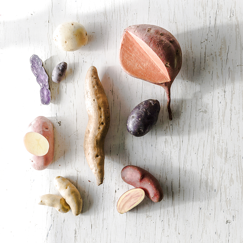 Variety of potatoes on white wooden table