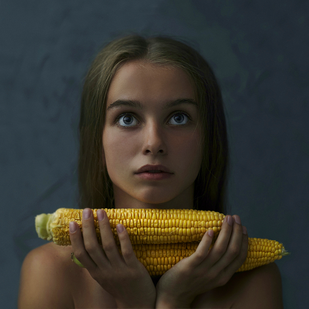 Caucasian girl holding corn on cob and looking up