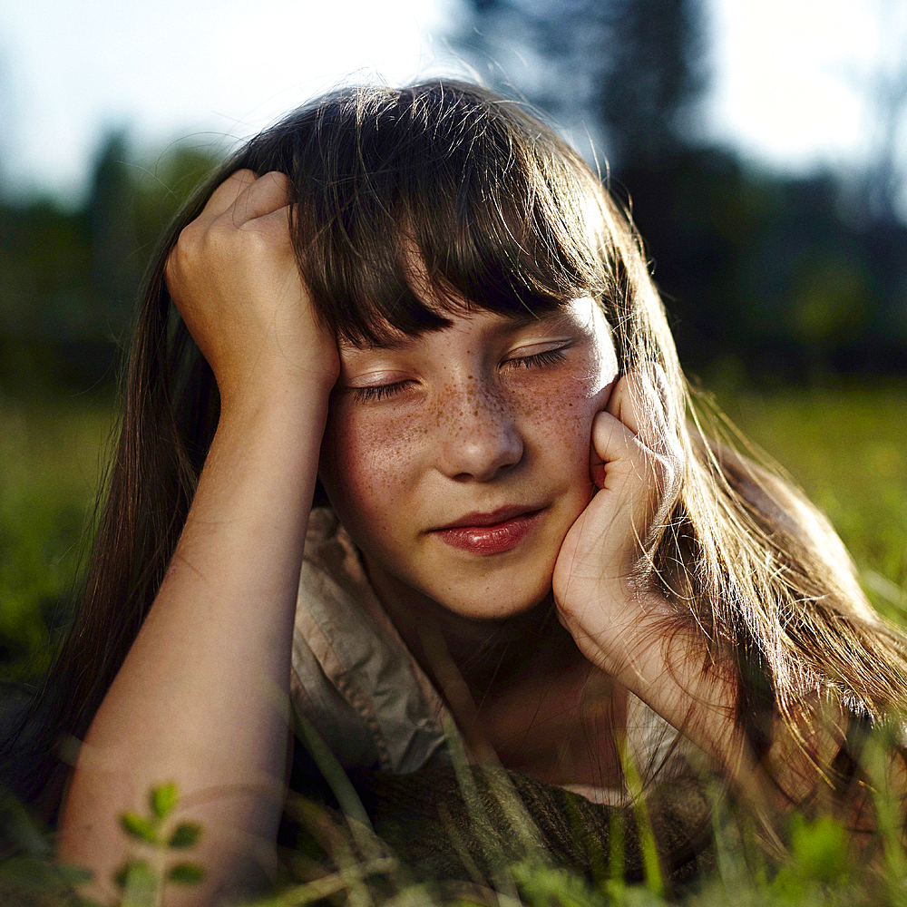 Caucasian girl with freckles laying in grass