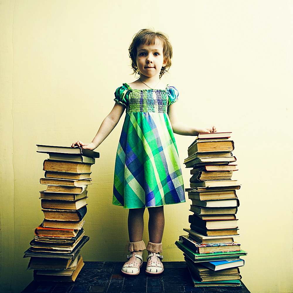 Caucasian girl standing with stacks of book