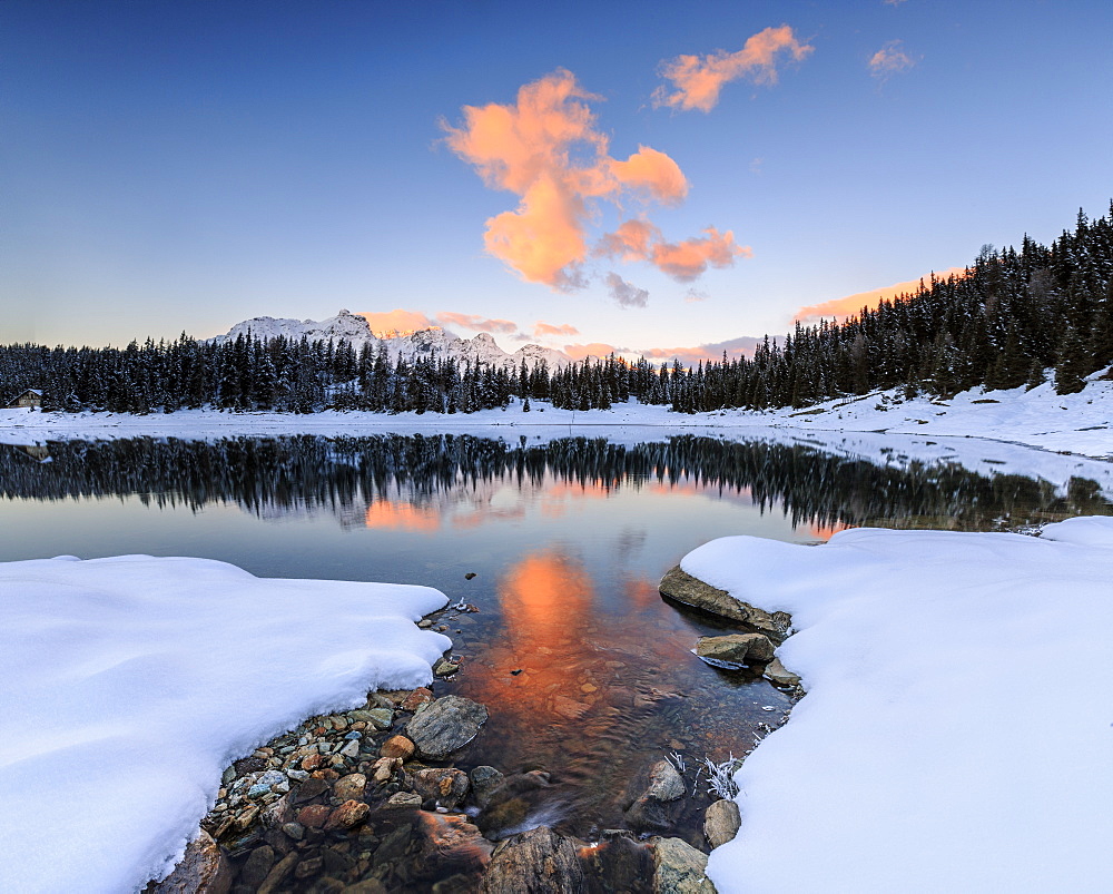 The colors of dawn on the snowy peaks and woods reflected in Lake Palu, Malenco Valley, Valtellina, Lombardy, Italy, Europe