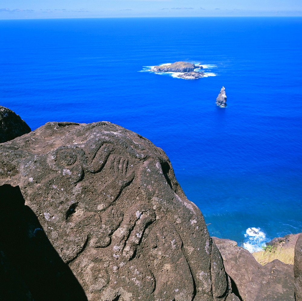 Birdman petroglyphs at Orongo ceremonial village on rim of crater Rano Kau, offshore lie bird islands of Motu Kao Kao, Motu Iri and Motu Nui, Easter Island, Chile, Pacific