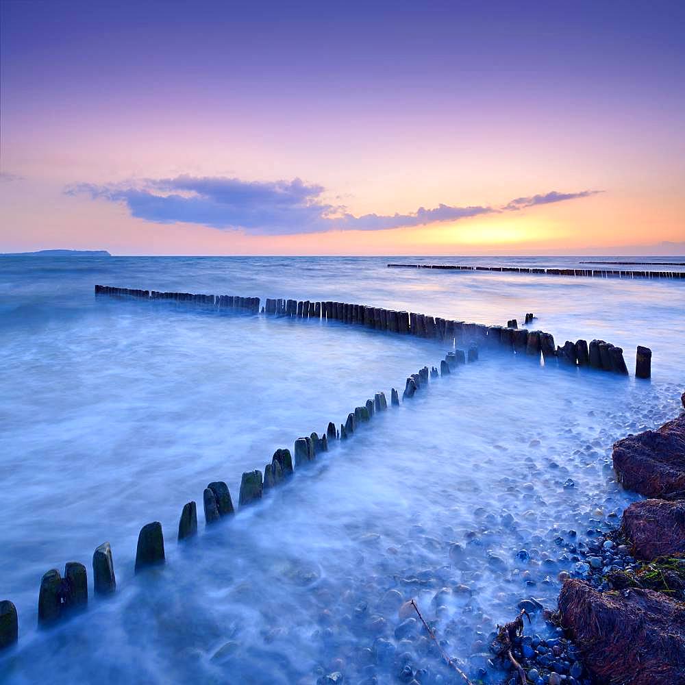 Sunset at the beach of the Baltic Sea, crossing groynes, on the horizon Hiddensee, island Ruegen, Mecklenburg-Western Pomerania, Germany, Europe