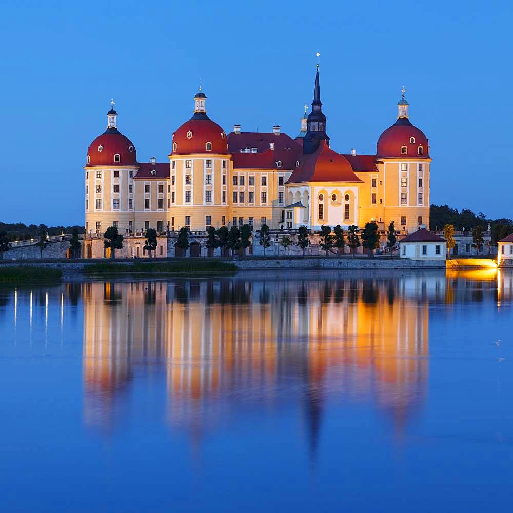 Illuminated Moritzburg Castle at dusk, water reflection in the lake, Saxony, Germany, Europe