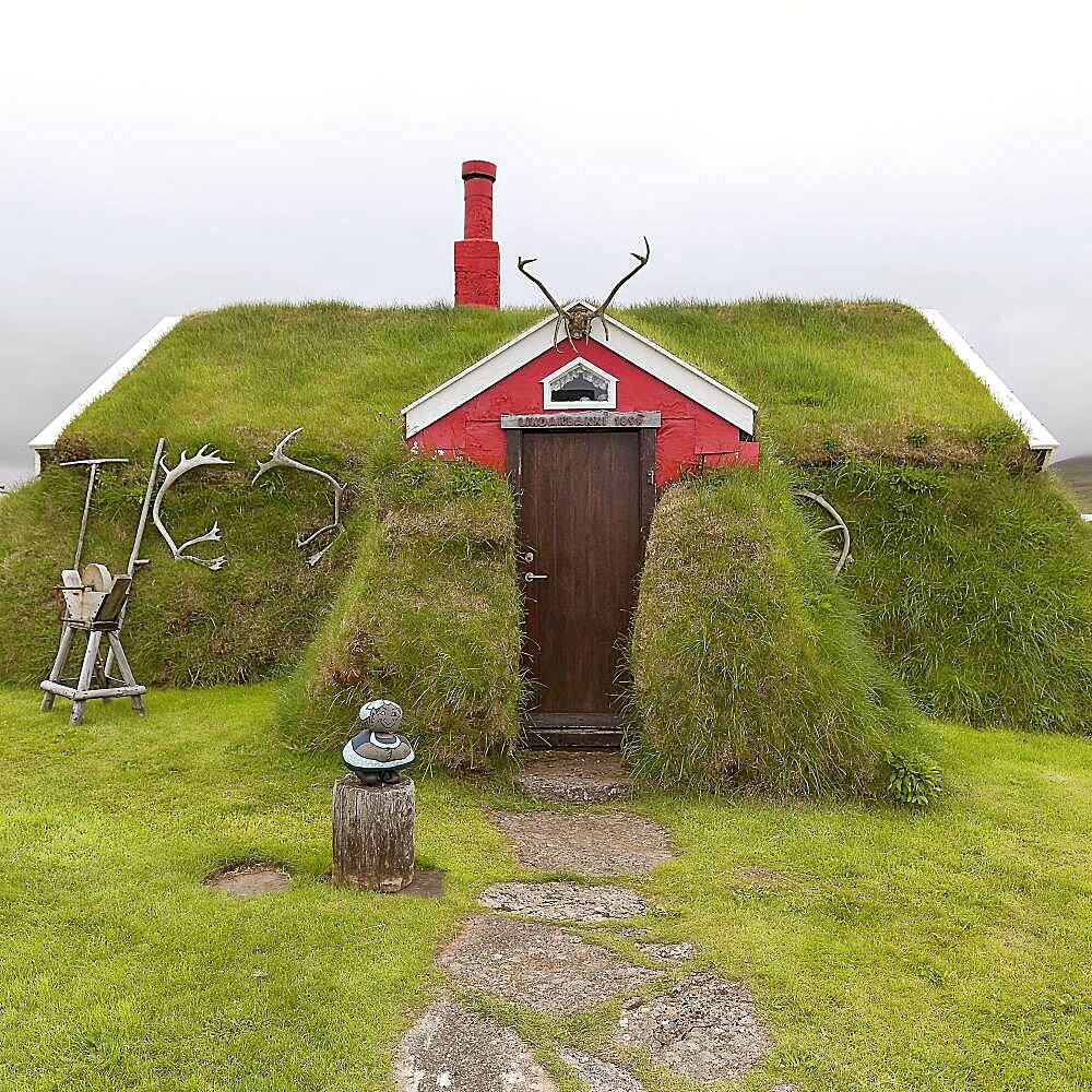 Traditional peat house Lindarbakki overgrown with grass and antlers in the red gable, Bakkageroi, Bakkagerdi, Borgarfjoerour, Borgarfjoerdur, Austurland, Iceland, Europe