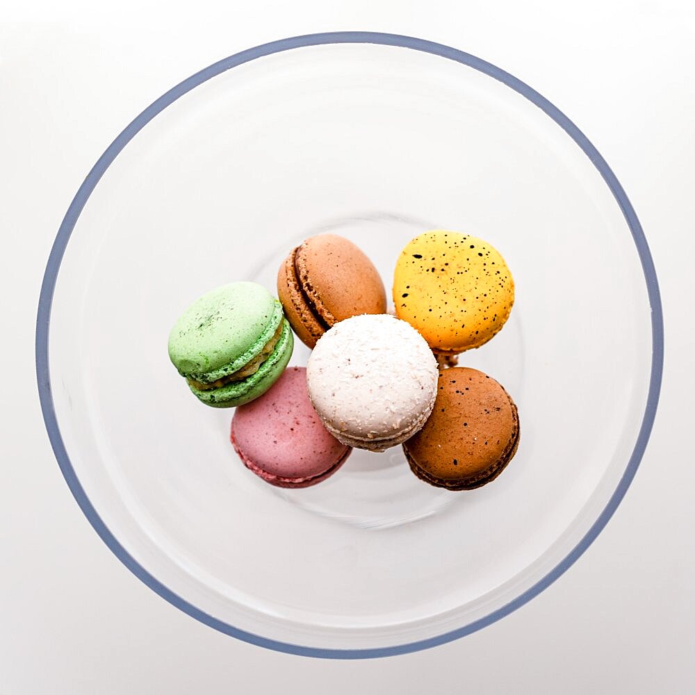 Top angle of colorful macaroons in a glass jar on a white table