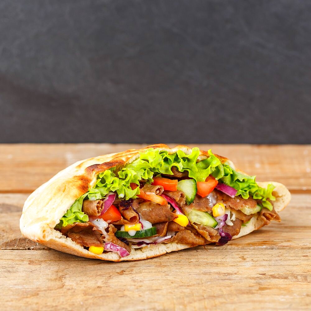 Doener Kebab Doner Kebap fast food food in pita bread on wooden board square copy space Copyspace in Stuttgart, Germany, Europe