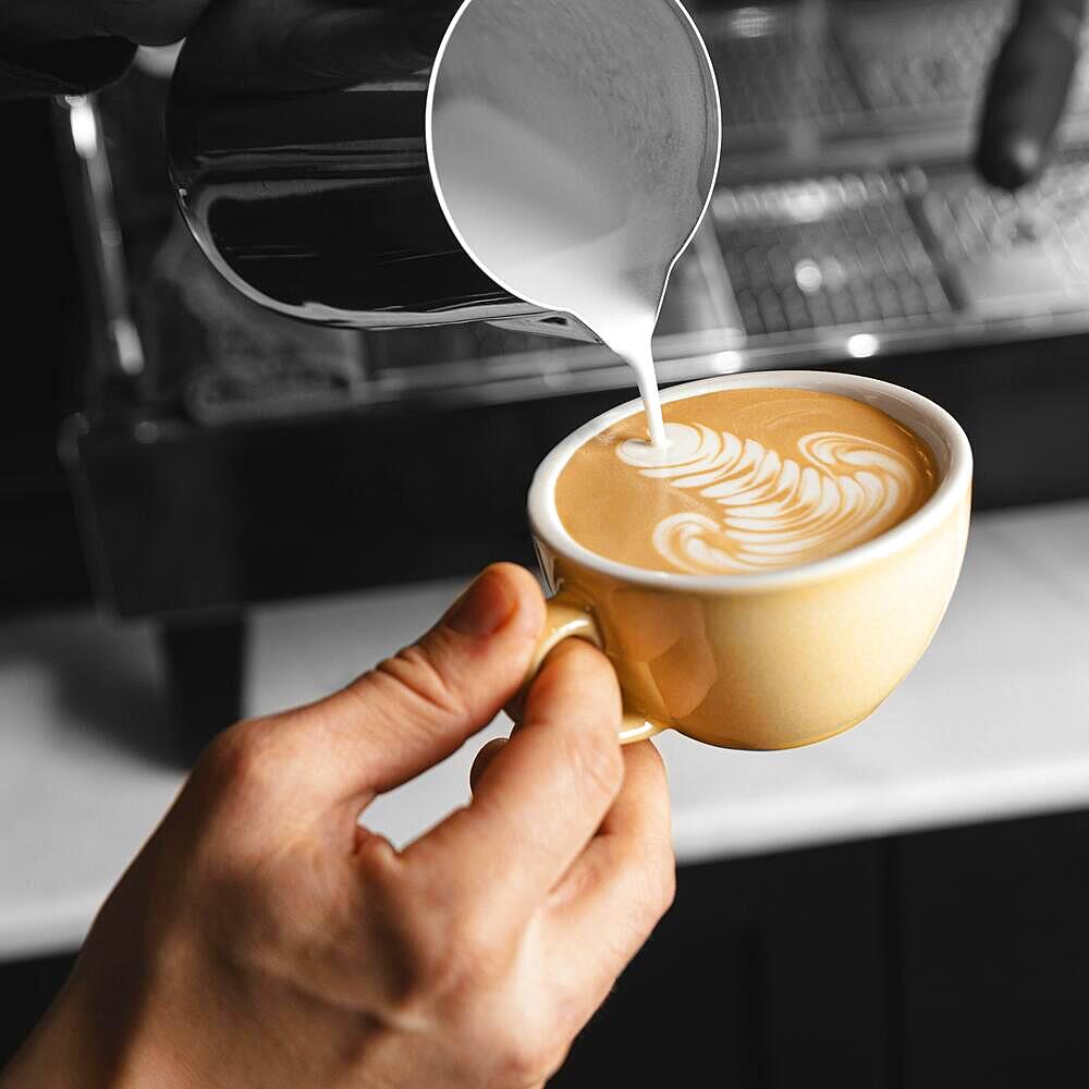 Close up hand pouring milk coffee cup