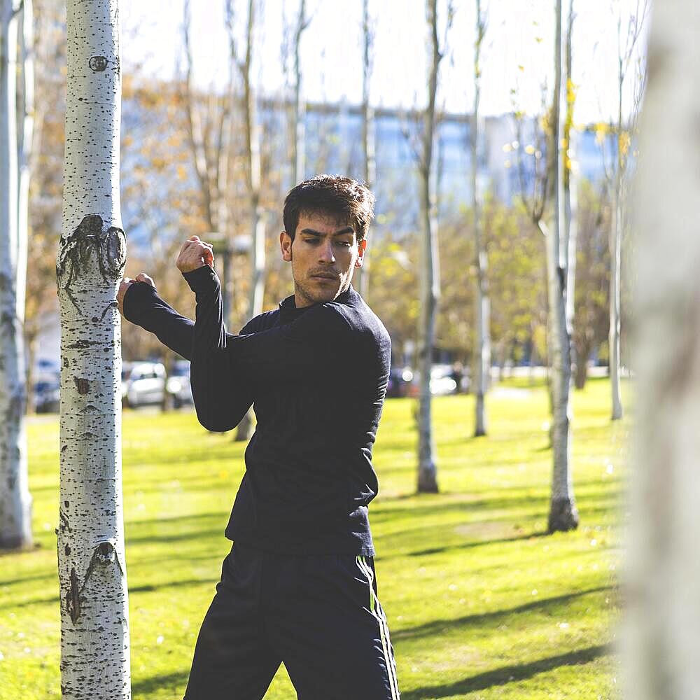 Young man stretching arms before jogging