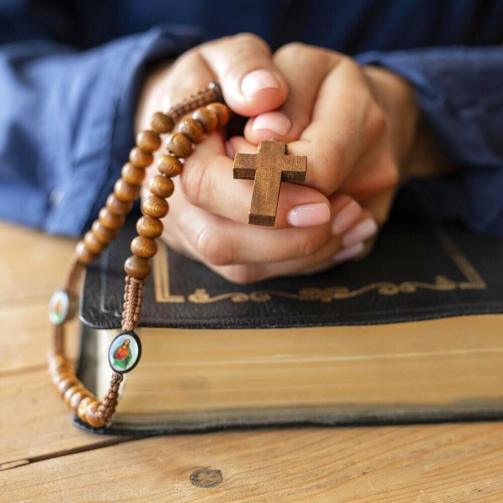 Person holding rosary hands praying