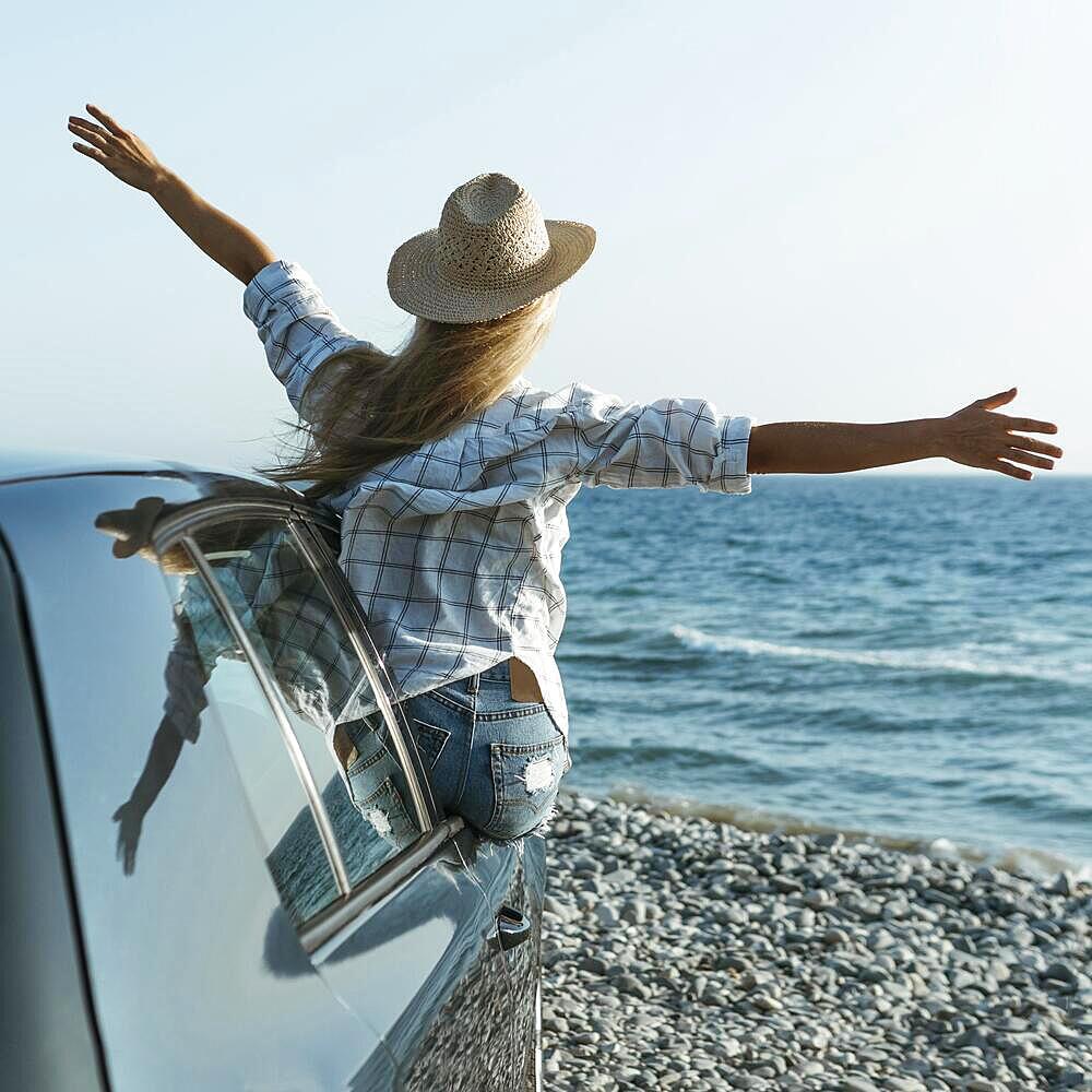 Blonde woman with hat standing out car window