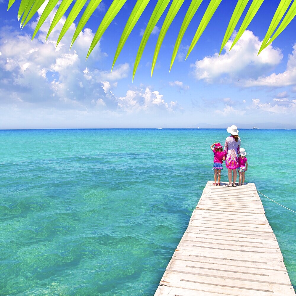 Daughters and mother in jetty on Formentera with turquoise sea