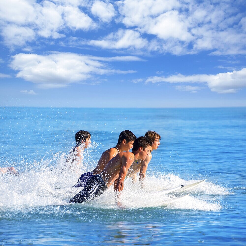 Boys teen surfers surfing running jumping on surfboards at the beach
