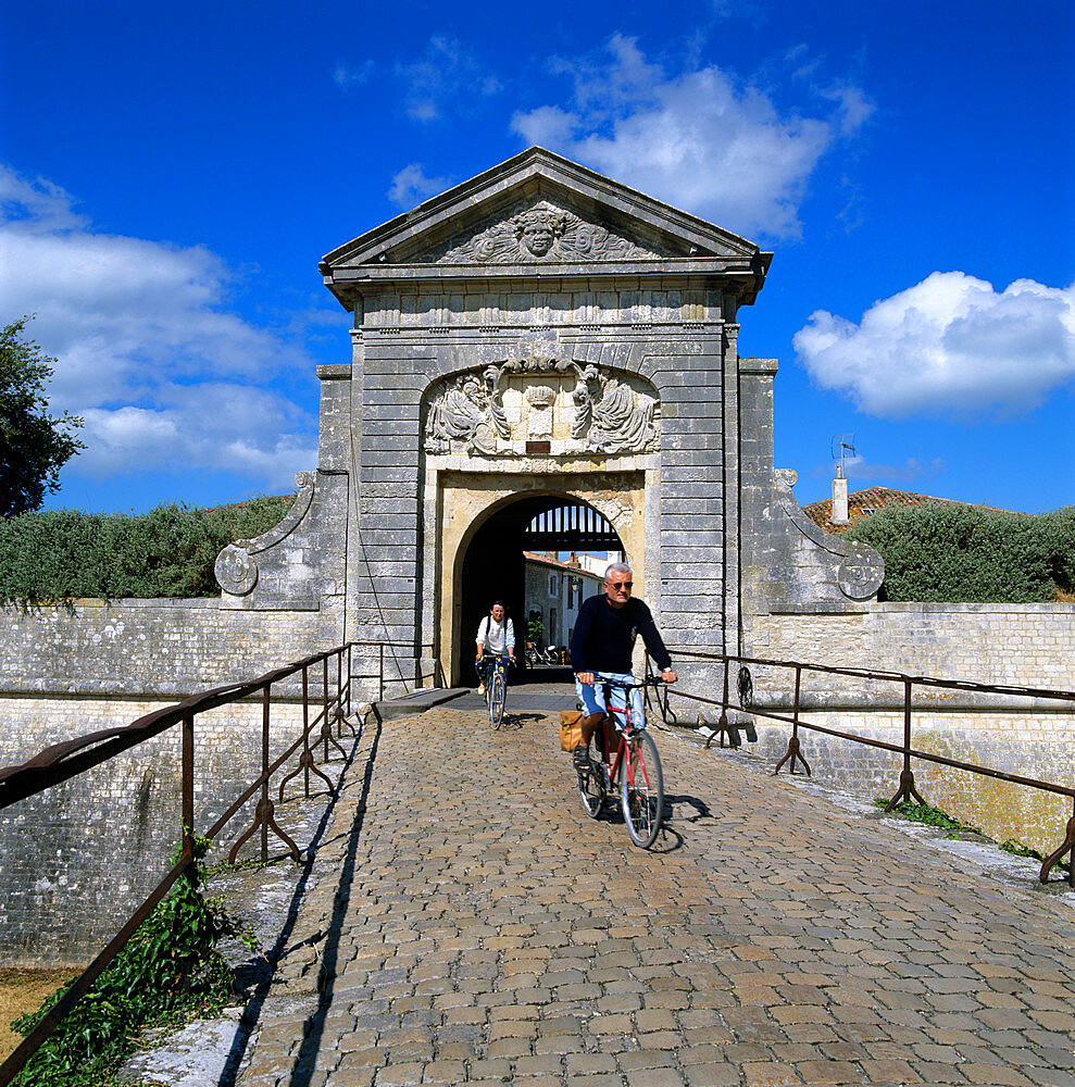 Fortifications and town gate with cyclists, St. Martin, Ile de Re, Poitou-Charentes, France, Europe