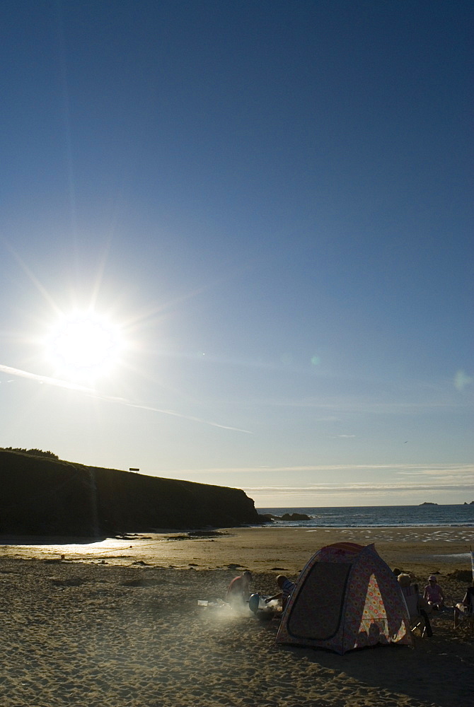 Family having BBQ on beach at sunset, Cornwall, UK