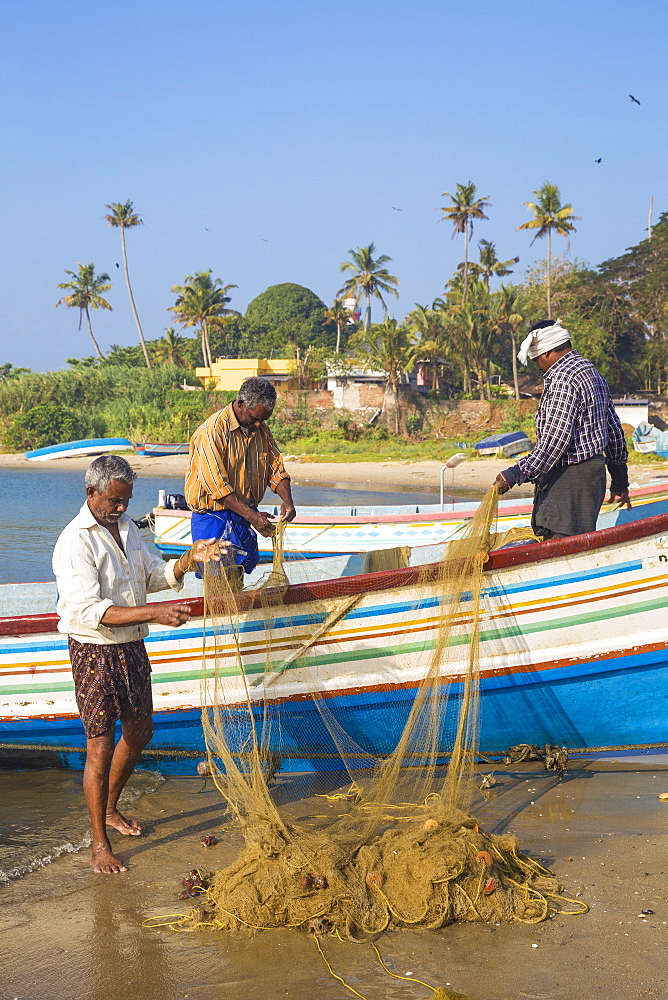 Fishing boats on beach with Tangasseri Lighthouse in background, Kollam, Kerala, India, Asia