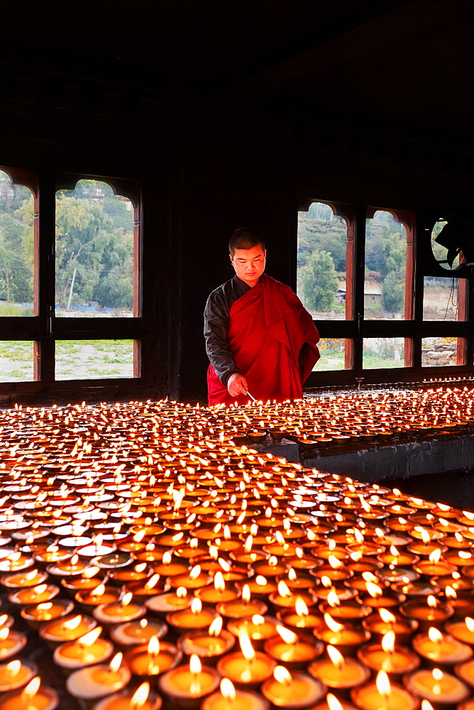 Portrait, Bhutanese Buddhist monk lights candles for worshippers to pray, Tamzhing Monastery, Bumthang District, Bhutan, Asia