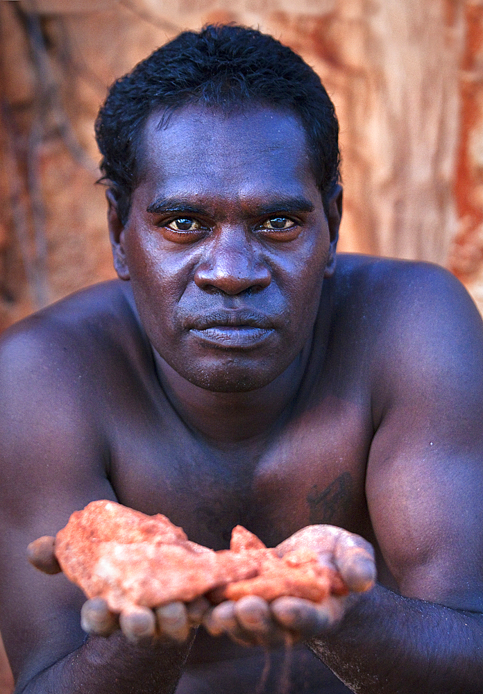 Portrait, Aboriginal man holding ancient red rock near Bawaka Homeland, East Arnhem Land, Northern Territory, Australia, Pacific