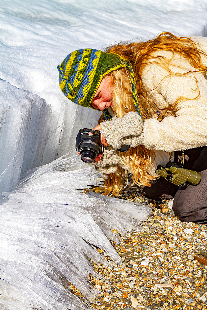 Guest from the Lindblad Expedition ship National Geographic Explorer photographing soda straw ice in the Svalbard Archipelago, Norway.