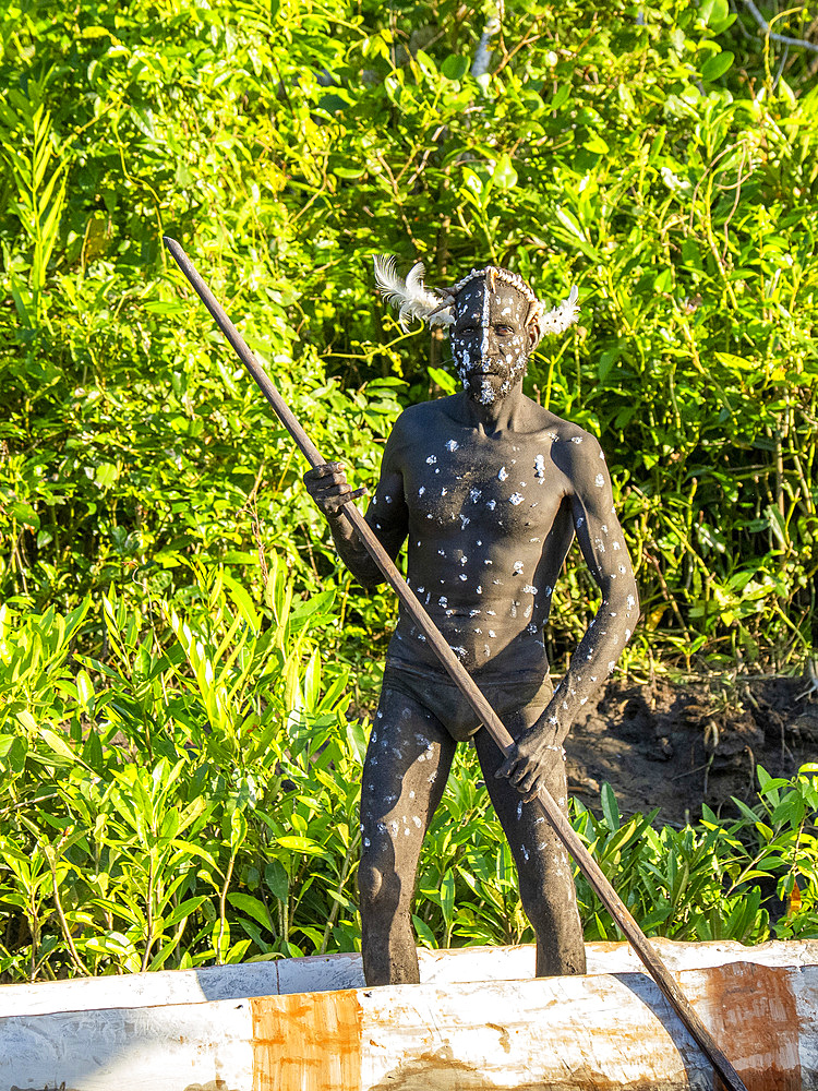Male paddlers from the village of Per perform in a ritualistic greeting ceremony, Asmat Region, Papua, Indonesia.
