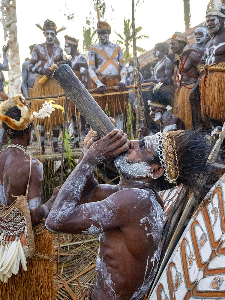 Male warriors from the village of Per perform a greeting ceremony in traditional regalia, Asmat Region, Papua, Indonesia.