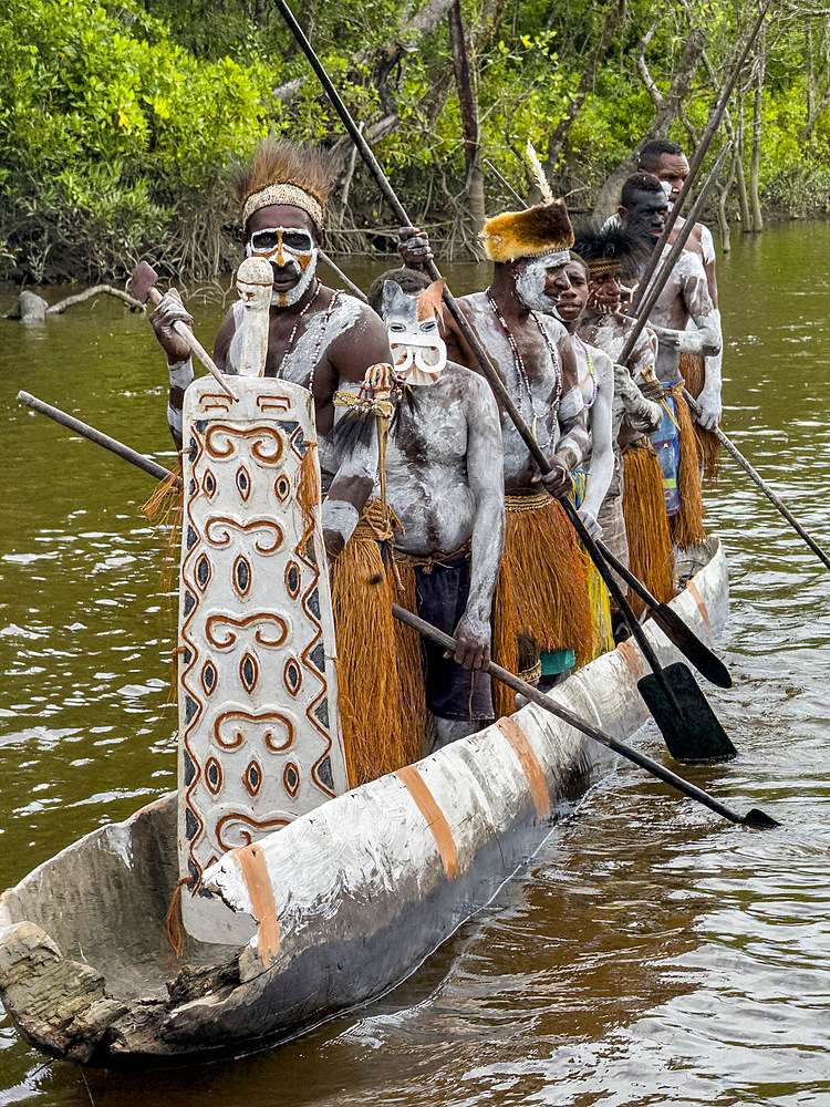 Male paddlers from the village of Uwus perform in a ritualistic greeting ceremony, Asmat Region, Papua, Indonesia.