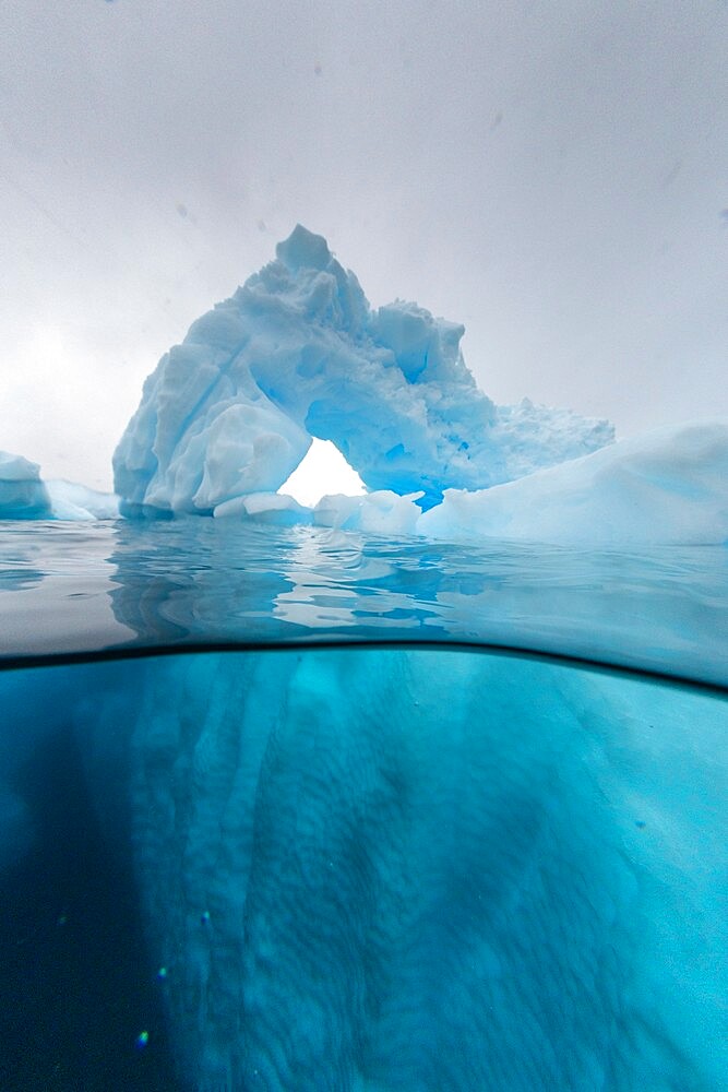 Above and below view of an arch formed in an iceberg at Cuverville Island, Ererra Channel, Antarctica, Polar Regions