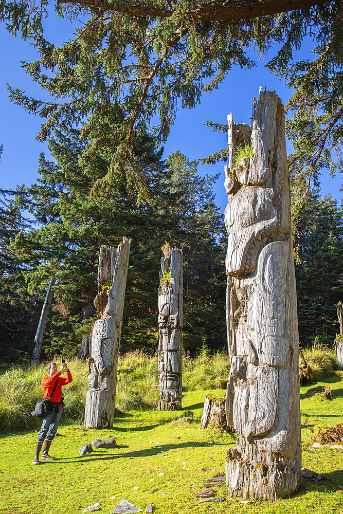 Photographer with totem pole at the UNESCO World Heritage site at SGang Gwaay, Haida Gwaii, BC.