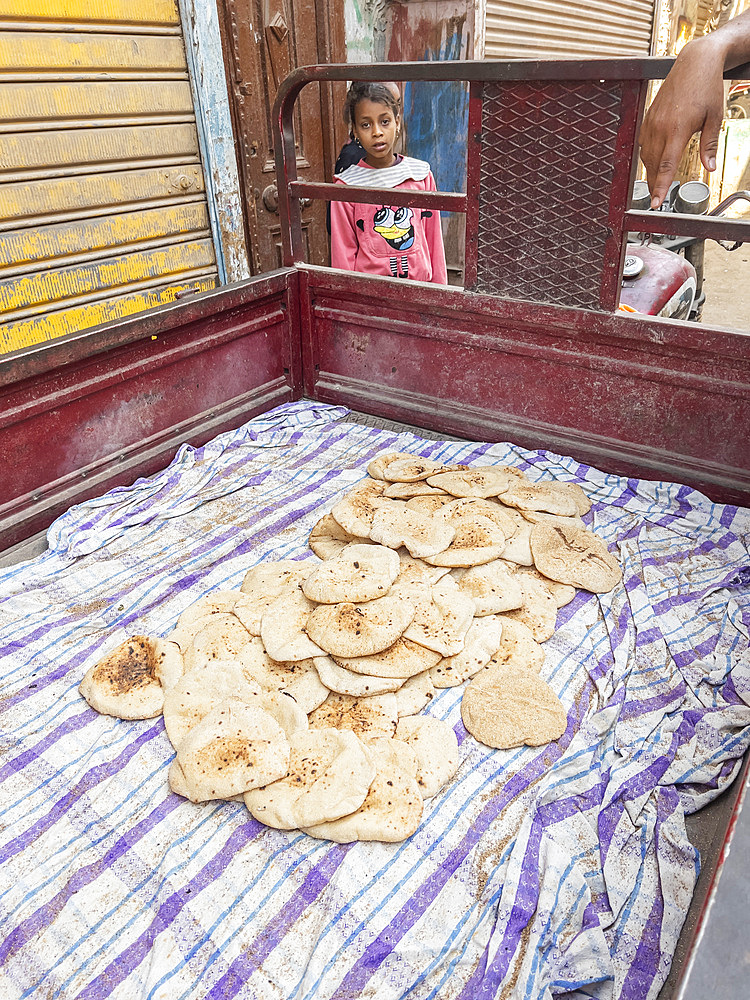 An Egyptian girl at a food cart in the heart of the city of Dendera, Egypt, North Africa, Africa