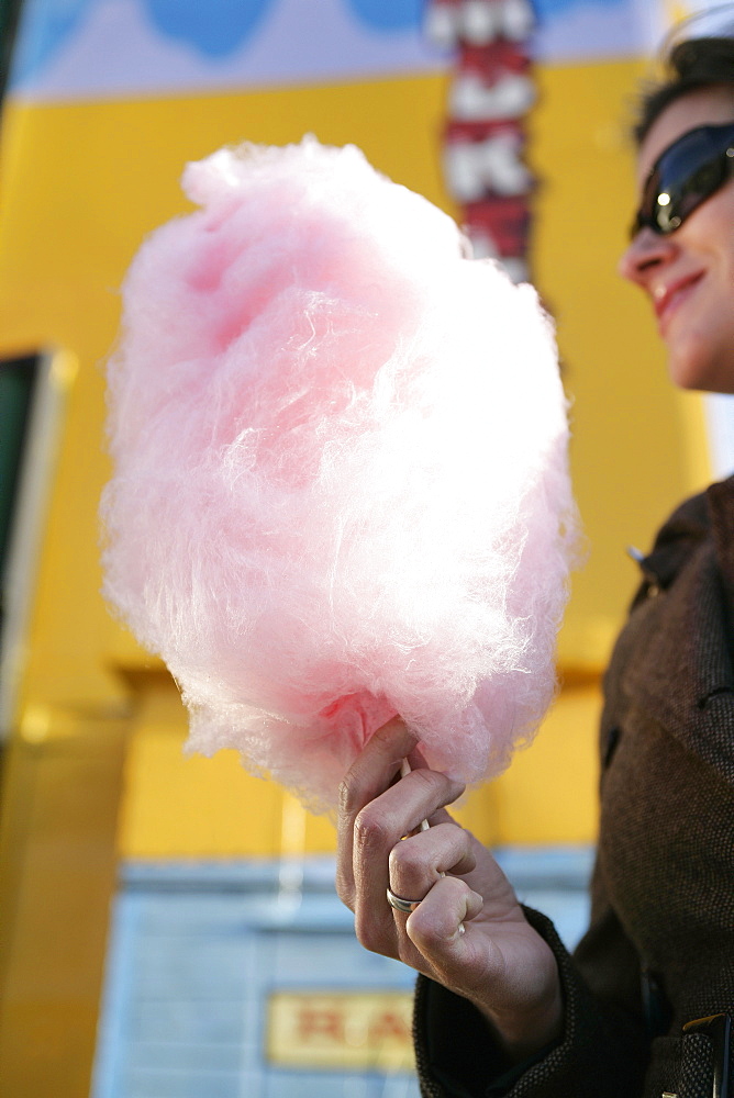 Mid adult woman with pink cotton candy, Prater, Vienna, Austria