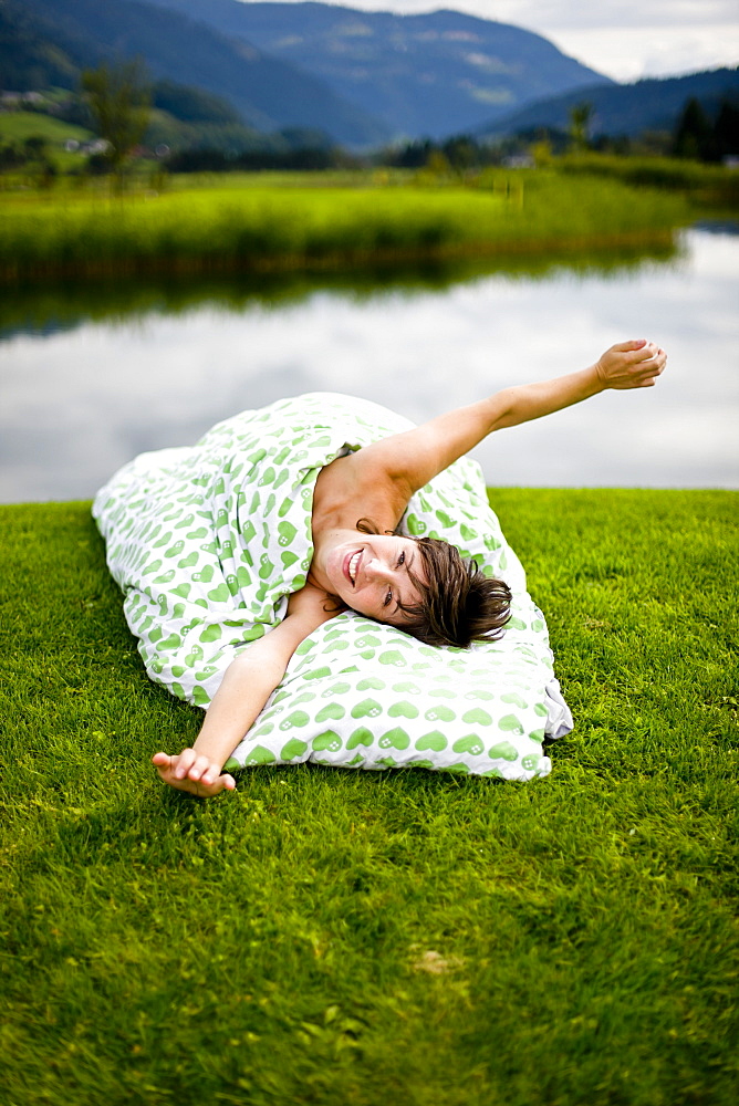 Woman lying with bedding on a golf course, Styria, Austria