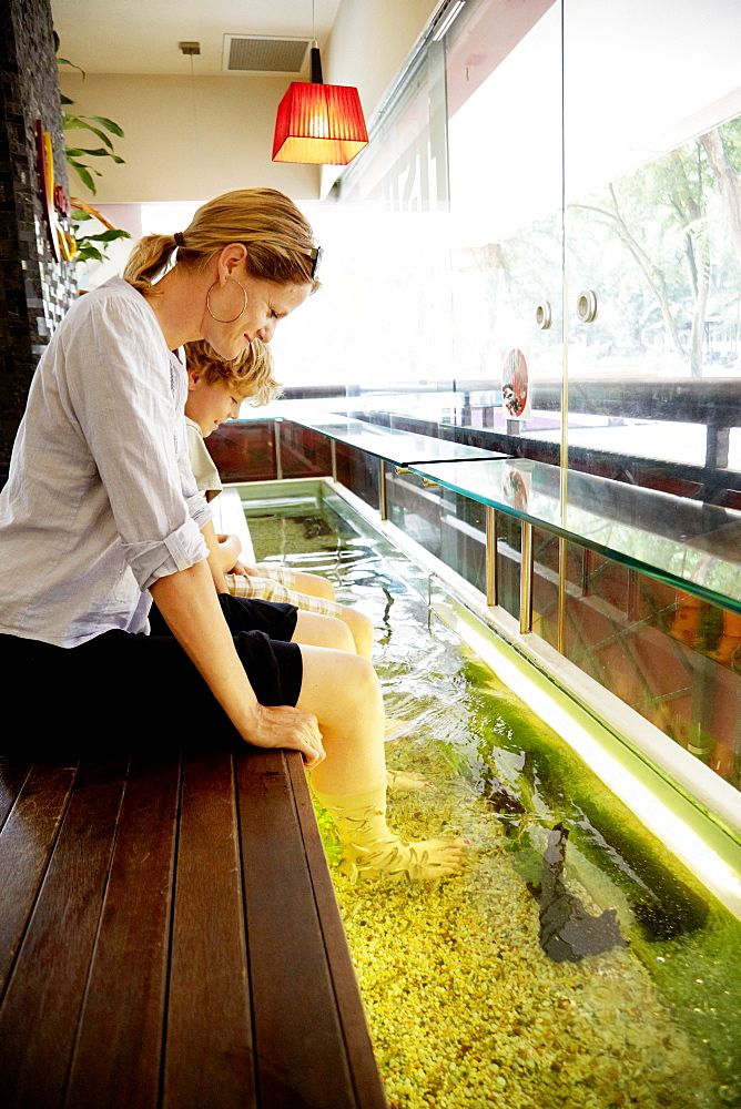 Woman and boy enjoying fish spa, Downtown Core, Singapore