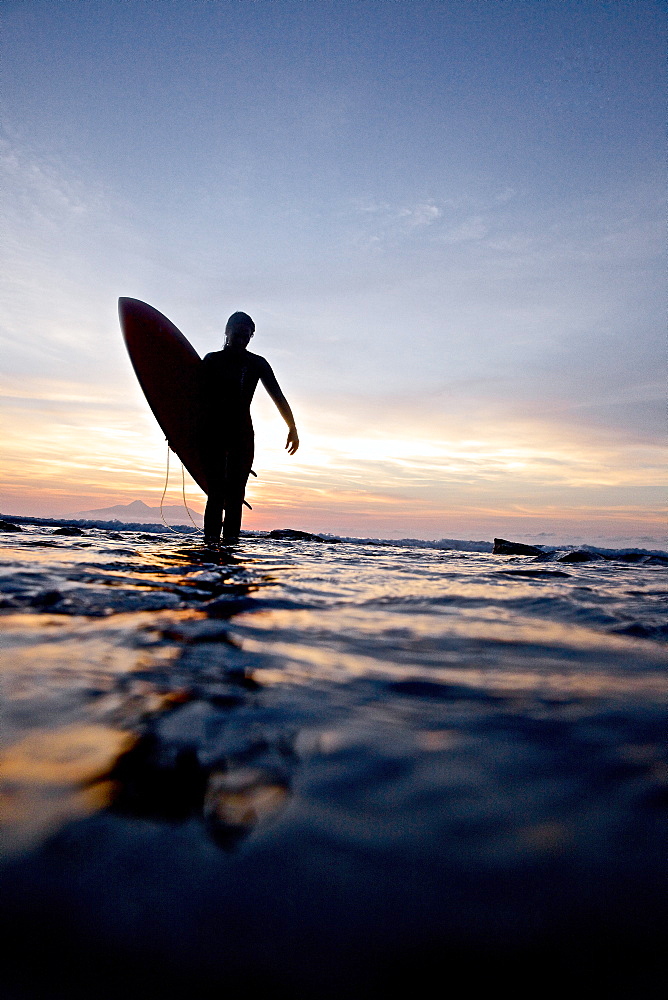 Female surfer carrying surfboard, Praia, Santiago, Cape Verde