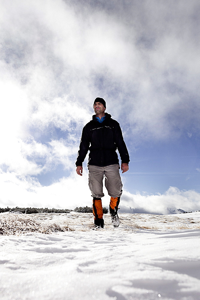 Hiker walking in snow-covered landscape, ascend to Unnutz Mountain (2078 m), Rofan Mountains, Tyrol, Austria