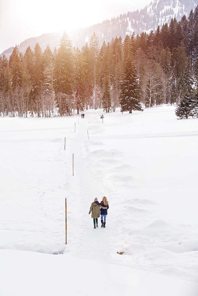 Two young women walking in snow, Spitzingsee, Upper Bavaria, Germany