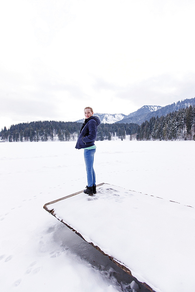 Young woman on a jetty at lake Spitzingsee, Upper Bavaria, Germany