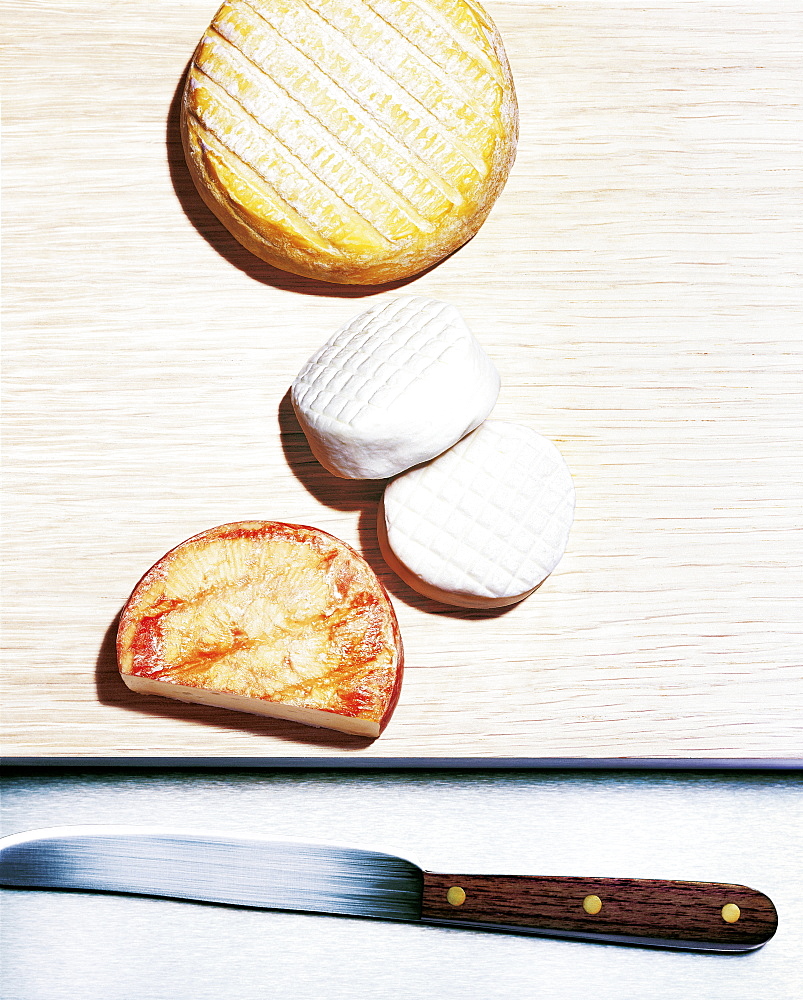 Various soft cheeses on a board with knife, Food