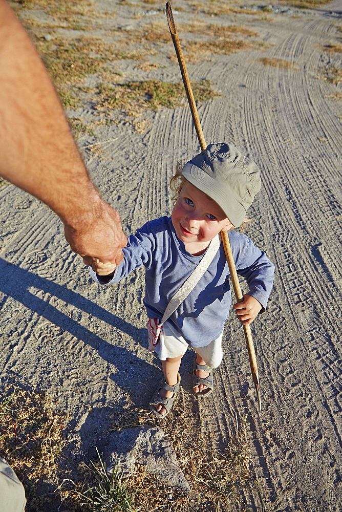 Father and son walking hand in hand, Kubu Island, Makgadikgadi Pans National Park, Botswana