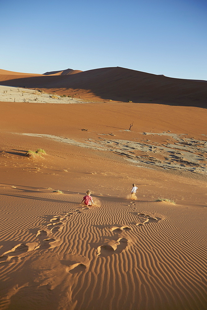 Two boys running down a sand dune, Deadvlei, Sossusvlei, Namib-Naukluft Park, Namibia