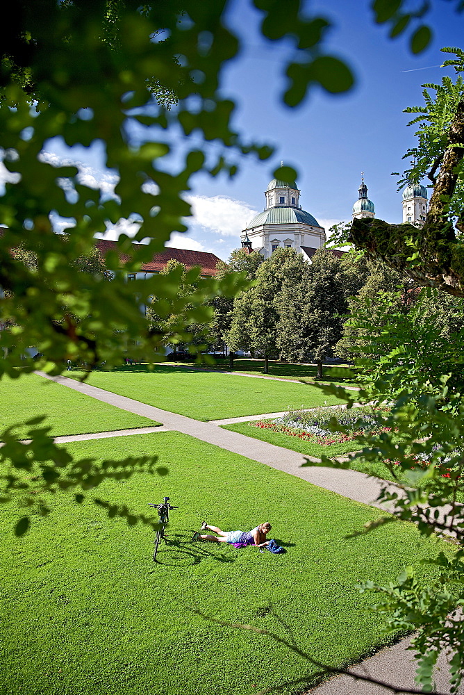 Young female cyclist having a rest in a beautiful park, Kempten, Bavaria, Germany