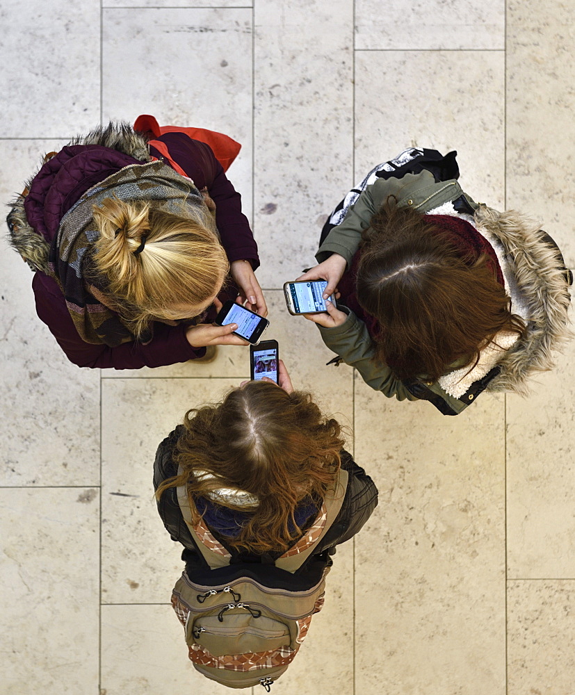 3 Girls chatting with smartphones in a shopping mall, Hamburg, Germany, Europe