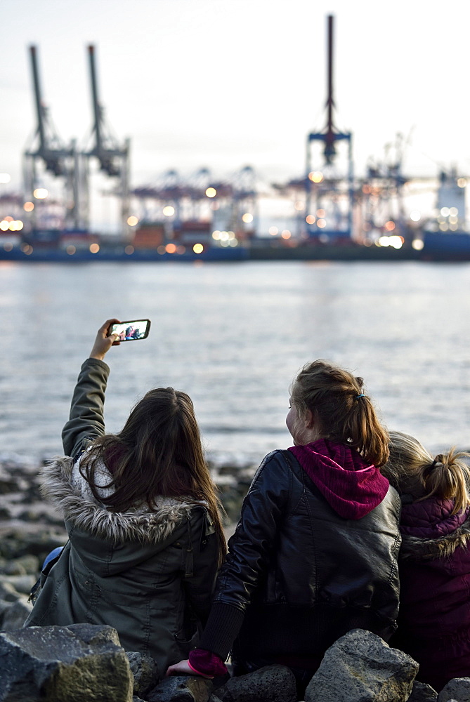 3 girls making selfie pictures at the Elbe River beach, Oevelgoenne, Hamburg, Germany, Europe