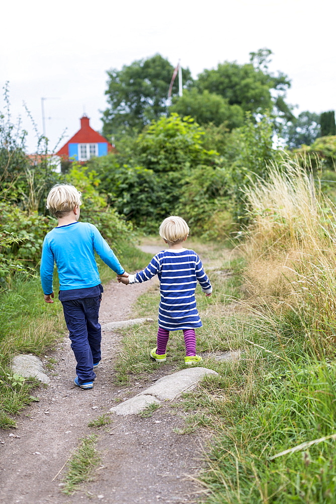 Siblings, children walking hand in hand, hiking trail from Svaneke to Listed, summer, Baltic sea, MR, Bornholm, Svaneke, Denmark, Europe