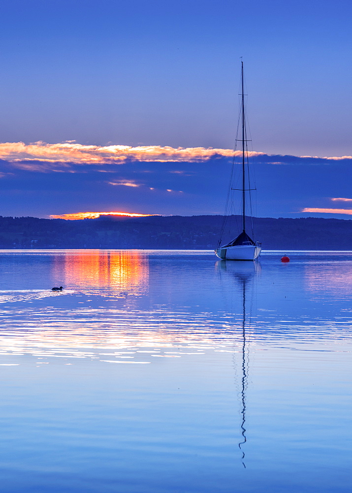 Boat in backlight at sunrise on Lake Starnberg, Tutzing, Bavaria, Germany