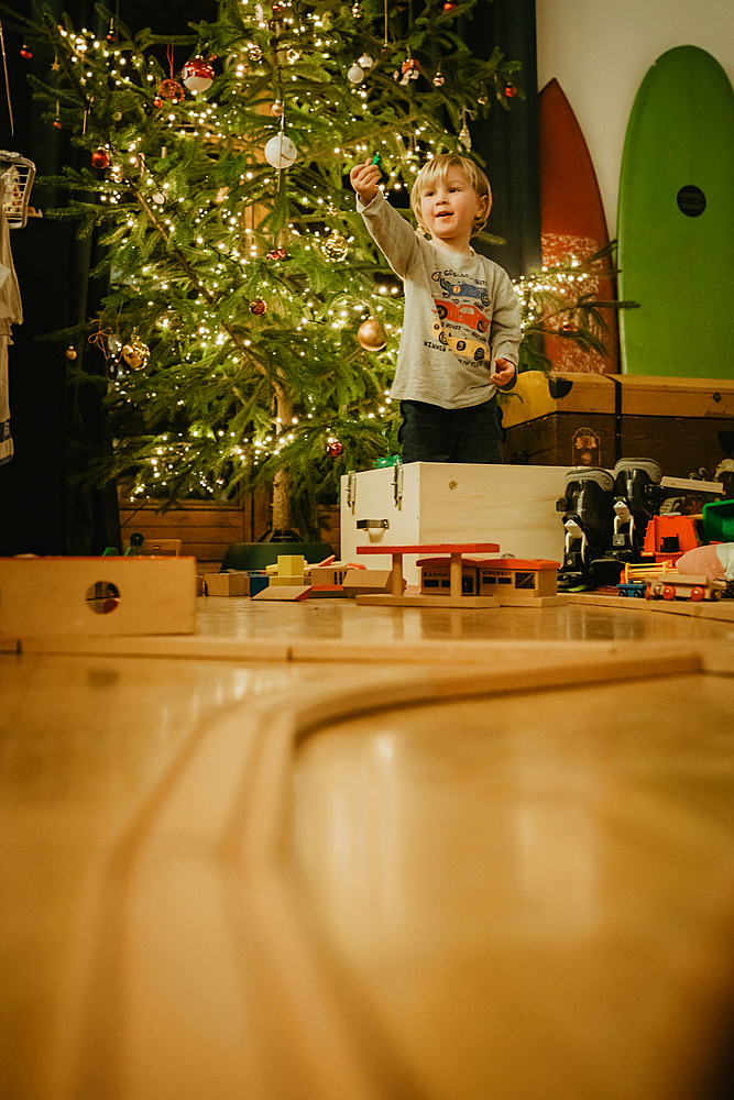 little boy playing with his wooden train in front of the Christmas tree, Christmas, family