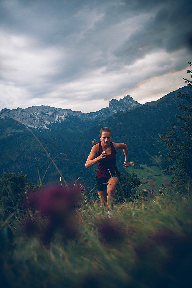 Young woman runs in the evening mood at Falkenstein, Allgäu, Bavaria, Germany