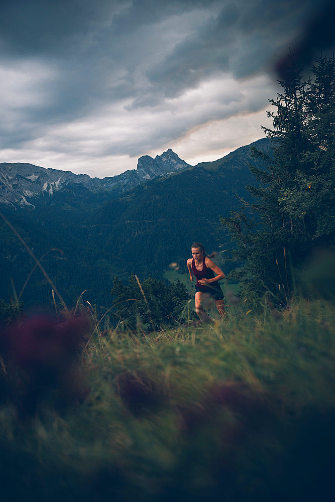 Young woman runs in the evening mood at Falkenstein, Allgäu, Bavaria, Germany