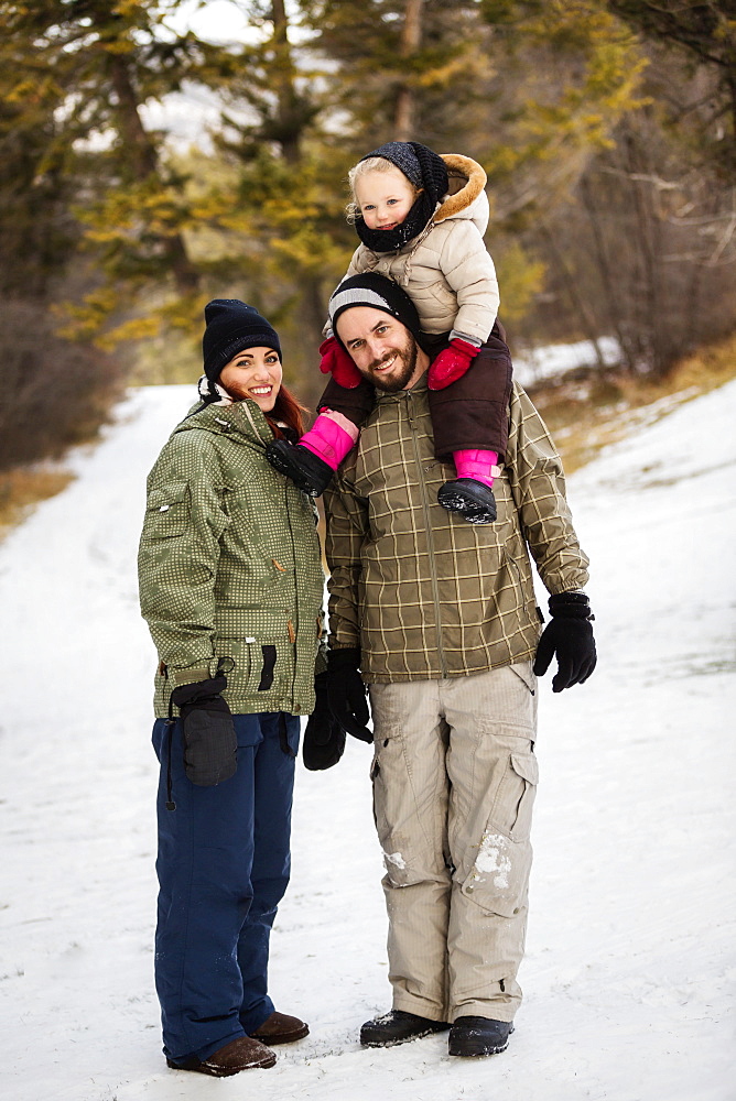 A young family hiking outdoors with their young daughter during a winter family outing: Fairmont, British Columbia, Canada