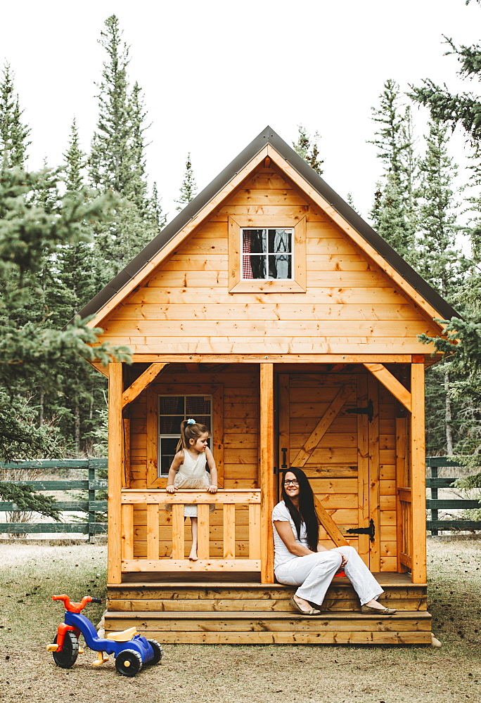 Mother and daughter with a wooden playhouse, Alberta, Canada