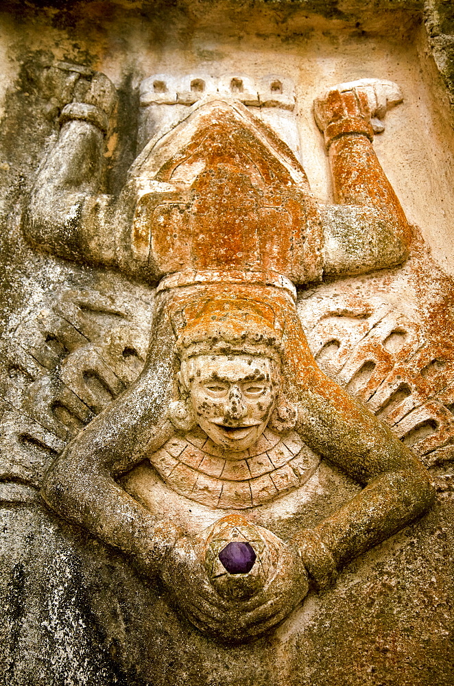 Close-up view of human figure splayed like a toad and holding a purple stone, carved on the side of a Mayan ruin, Tulum, Quintana Roo, Mexico